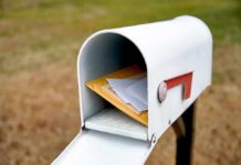 White mailbox with red flag holding envelopes and padded mailers