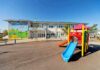Taxpayers Bled by Phantom Daycare Playground with colorful slide in front of a school building
