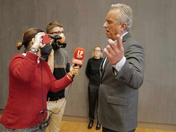 Robert F. Kennedy Jr. speaking to reporters with microphones and a camera