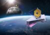 space telescope with gold hexagonal mirror orbiting above Earth