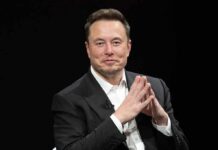 Elon Musk seated in a black suit with hands clasped