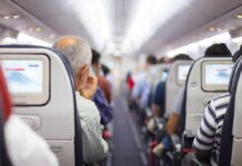 One Flight Meltdown Cost Him More Than Expected Airplane cabin aisle with passengers seated and seatback screens