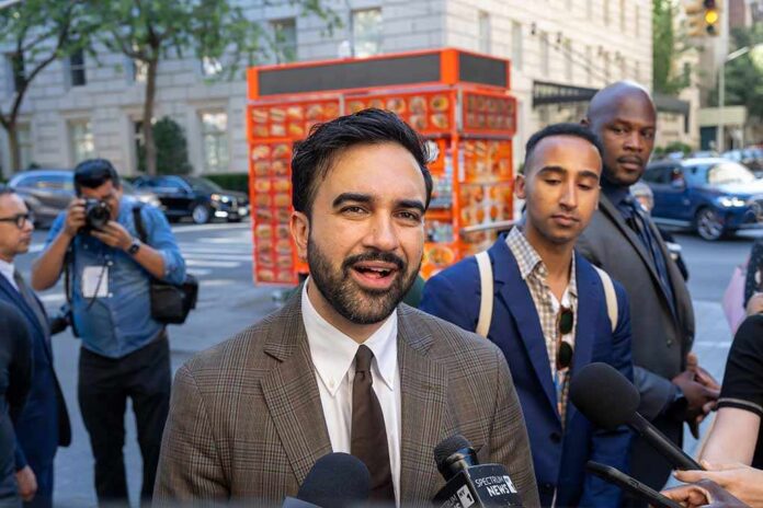 Zohran Mamdani speaking to reporters on a city sidewalk