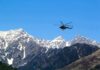 Helicopter flying over snow-capped mountain range
