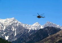 Helicopter flying over snow-capped mountain range