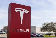 Tesla’s Robotaxi Audited – Scale Or Stall? Tesla dealership sign in front of parking lot