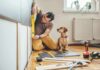 Man measuring cabinet with a level as a small dog watches