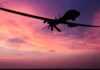 drone silhouette flying against a pink and purple sunset sky