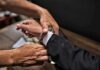 hands placing handcuffs on a suited person's wrists