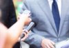 Reporter holds microphone toward person in suit during interview
