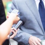 Reporter holds microphone toward person in suit during interview