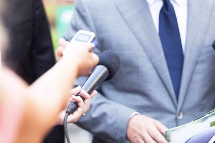 Reporter holds microphone toward person in suit during interview