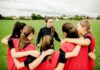 Coach talks to youth team in a huddle on a field