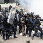 Dontrelle Inman and Tom Mandrake among riot police advancing with shields in tear gas