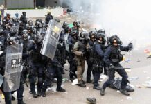 Dontrelle Inman and Tom Mandrake among riot police advancing with shields in tear gas
