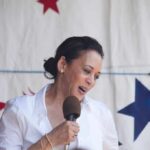 woman speaking into a microphone on a star-patterned backdrop