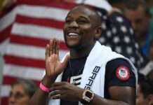 Floyd Mayweather Jr. smiling and cheering with a towel over his shoulders