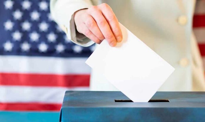 shutterstock_1659823591 Hand placing ballot into a box