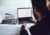 Person working at a laptop with blank screen on a desk