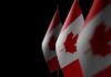 Canadian flags with maple leaf on dark background