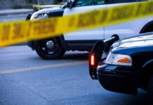 Police cars behind yellow caution tape at a street scene