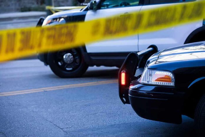Police cars behind yellow caution tape at a street scene