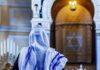A Streamer’s Remarks Ignite a Democratic Party Dispute Person in white and blue prayer shawl facing ornate interior