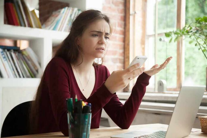 Woman frustrated with smartphone at desk