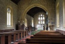 Church interior with wooden pews and stained glass altar